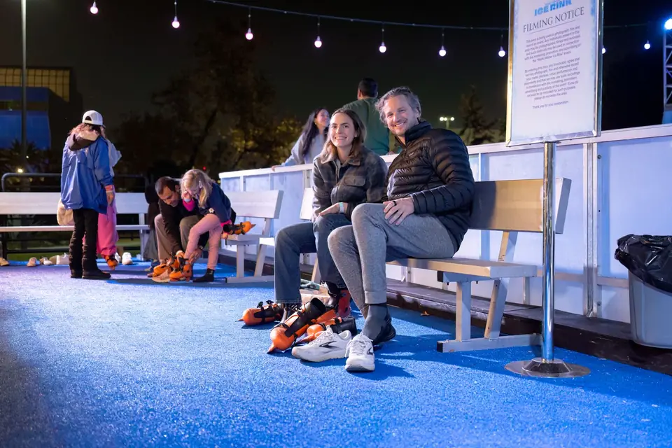 Skaters lacing up on a rinkside bench