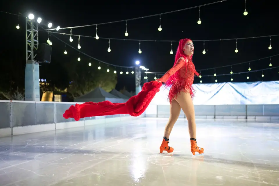 A skater in a red cape gliding across the ice
